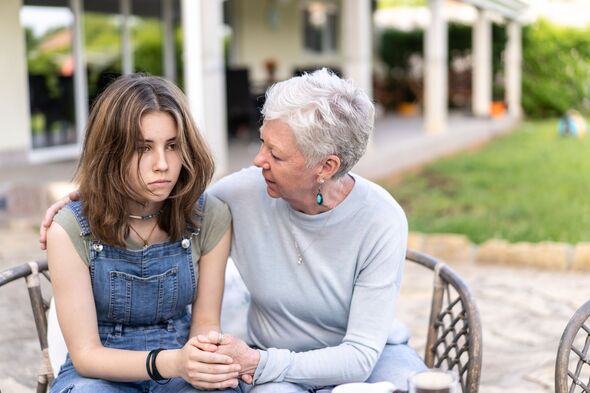 A forlorn teenager is being comforted by her grandmother