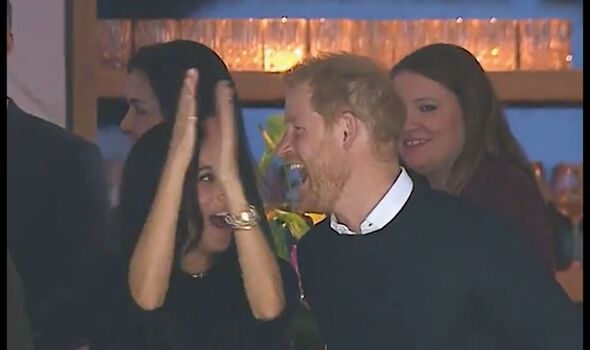 Harry laughs while Meghan claps at ice hockey